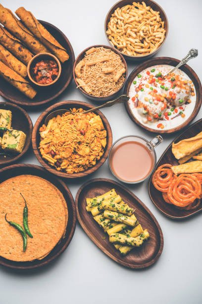 Group of Gujarati snacks like jalebi-fafda, thepla, khaman dhokla, aloo bhujiya, khandvi,khakra, dahi vada, gathiya with hot tea
